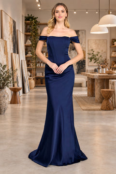 A woman wearing a navy blue, off-the-shoulder Amelia Couture 6151 gown with a corset bodice.
