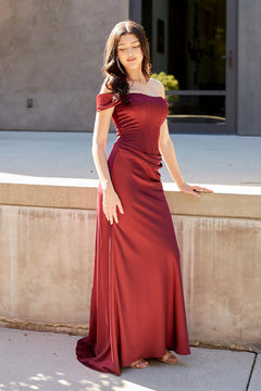 A person wearing a burgundy Amelia Couture 6151 off-the-shoulder, floor-length gown with a corset-style bodice.