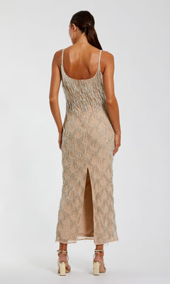 A woman stands with her back to the camera, wearing the Mac Duggal 6172 Long Formal Dress—a sleeveless midi dress featuring intricate beaded fringe details and a back slit—paired with strappy heels, all set against a plain white background.