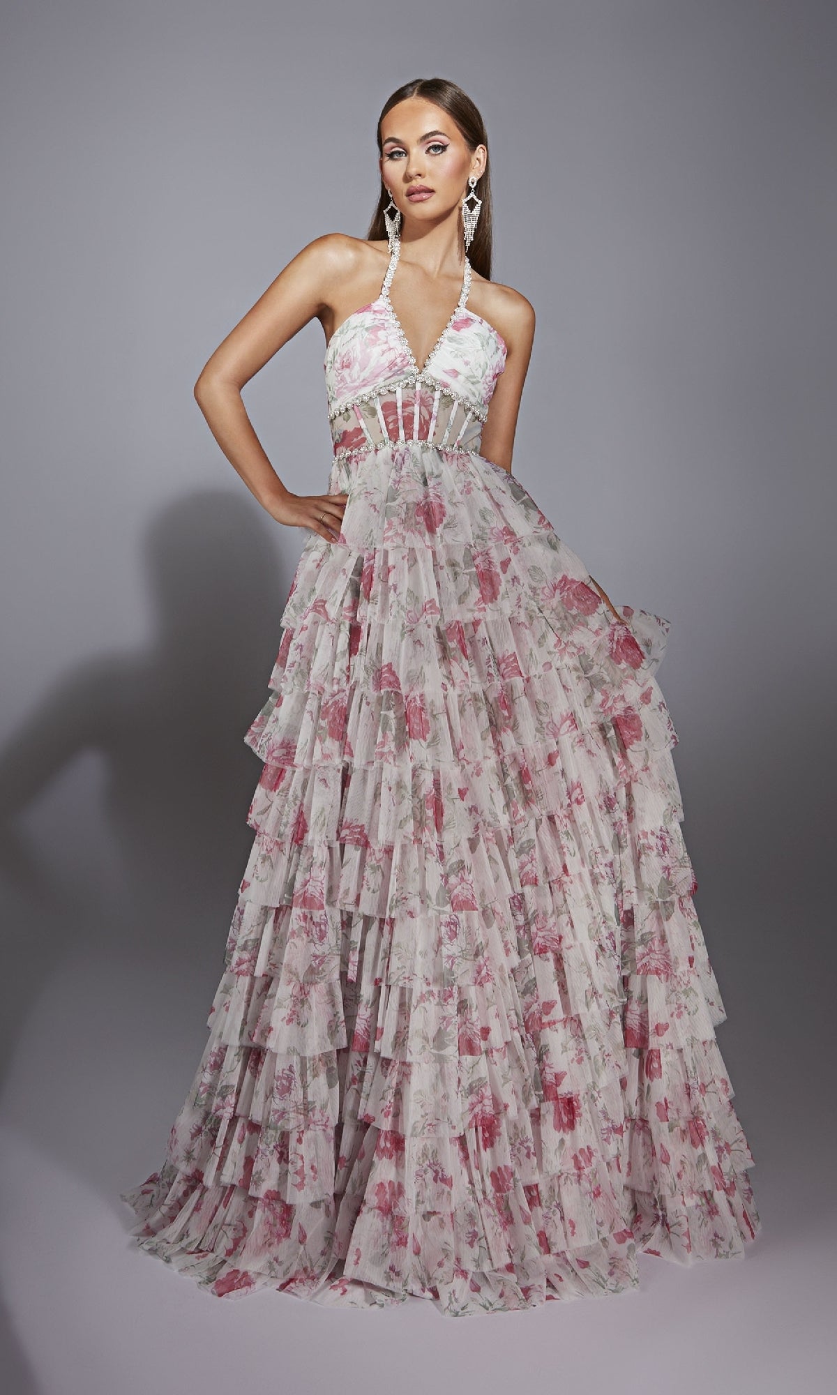 Model wearing the Alyce 61730 Ruffled Long Print Prom Dress, a sleeveless halter-neck gown with a tiered ruffled skirt and pink floral print, styled as a stunning floor-length evening look against a plain gray background.