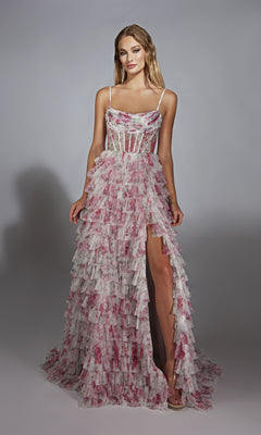 A woman models the Alyce 61732, a sleeveless, floor-length pink and white prom dress with floral patterns, ruffles, a corset bodice, and high slit, standing against a plain backdrop.