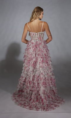 A woman is photographed from the back in the Alyce 61732 long prom dress, a pink and white floral tiered tulle gown with a ruffle A-line skirt and fitted corset bodice, against a plain gray background.