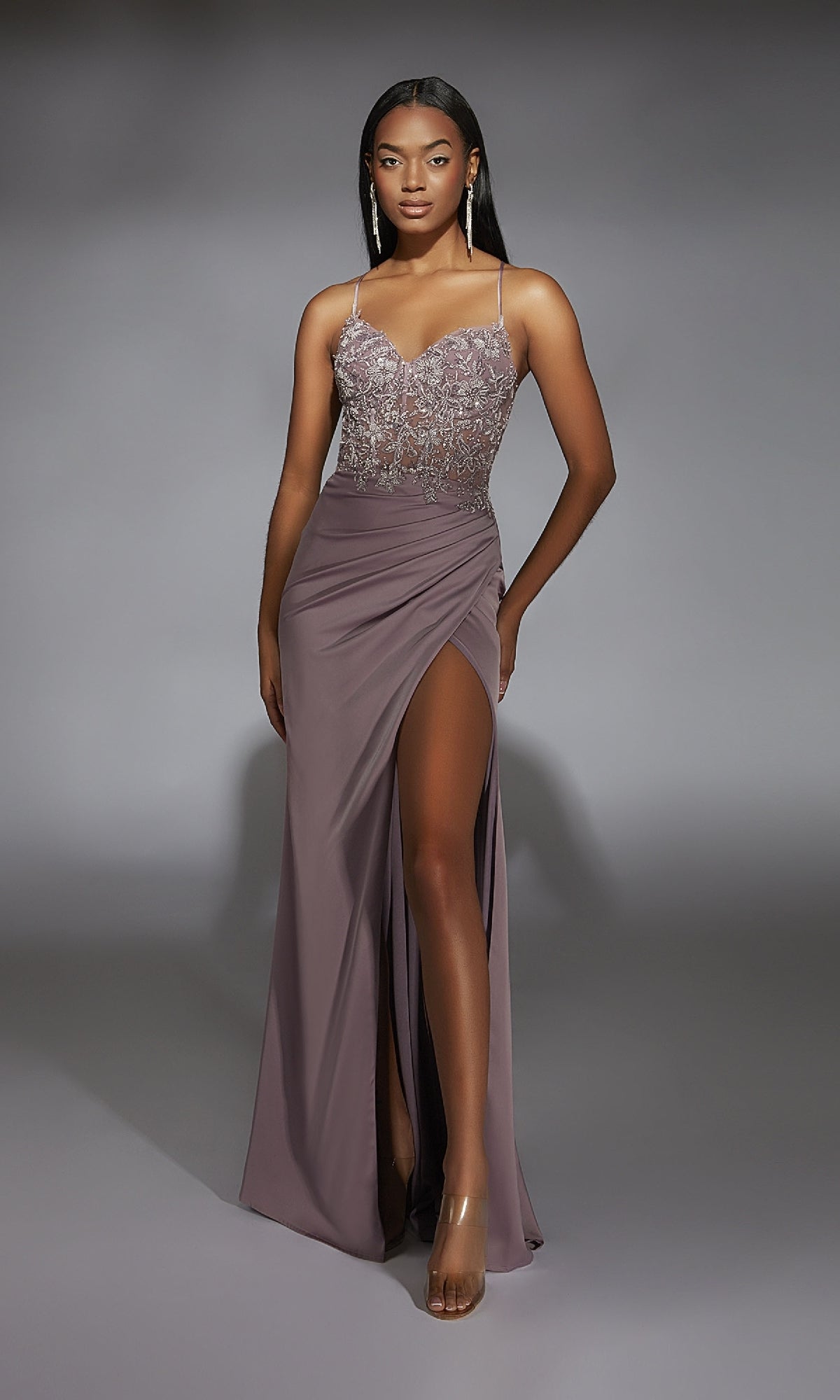 A woman wearing the Alyce 61741 Beaded-Lace-Corset Long Prom Dress with thin straps and a high-slit skirt stands against a plain gray background.