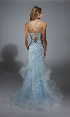 A woman stands facing away against a gray background, wearing the Alyce 61749 Long Prom Dress in light blue, featuring sheer tulle, a lace-up corset bodice, and a layered skirt.