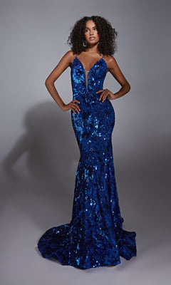 A woman poses in a studio, hands on hips, wearing the Lace-Up Long Sequin Prom Dress: Alyce 61755—a fitted, floor-length deep blue gown with thin straps and a plunging neckline—against a neutral background.