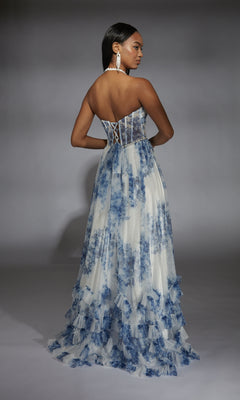 A woman stands against a gray background in the Alyce 61757 long prom dress—a strapless, floor-length white gown with blue floral prints and a lace-up back, offering a modern take on classic 80’s prom style.