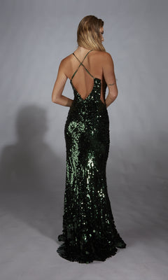 A person wearing the Alyce 61765 Sleek Long Sequin Prom Dress in dark green, with a low back and crisscross straps, stands against a plain backdrop.