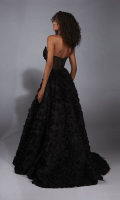 A person with curly hair wears the Alyce 61775 Strapless Rosette Prom Ball Gown, featuring a corset-style bodice and textured, voluminous skirt, standing facing away in a studio.