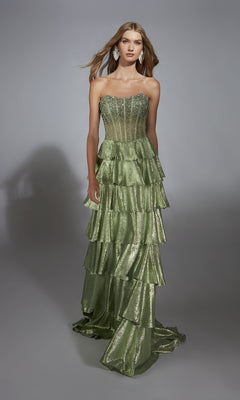 A woman wears the Alyce 61783 long prom dress in metallic green, with a strapless embellished corset bodice and tiered ruffled A-line skirt, standing against a plain gray background.