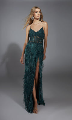 A woman models the Alyce 61788, a long dark green prom dress featuring spaghetti straps, a high slit, fringe details, and sheer waist sections in a studio setting.