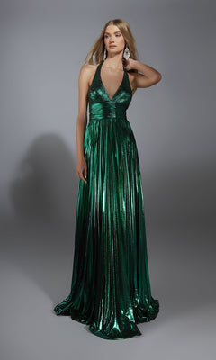 A woman models the Alyce 61792 long prom dress, a metallic green V-neck gown with a sleeveless halter top and floor-length A-line skirt, standing before a plain gray background.