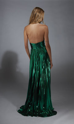 A woman with long blonde hair models the Alyce 61792, a metallic green, floor-length A-line prom dress, standing with her back to the camera against a plain gray background.