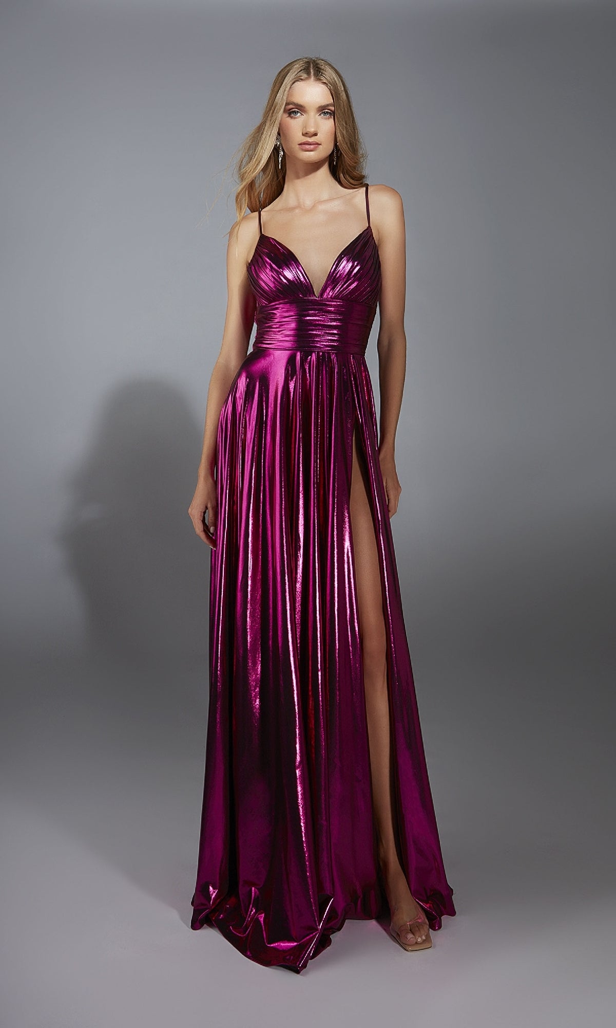 A woman in the Long Metallic A-Line Prom Dress: Alyce 61801, featuring thin straps, a v-neckline, and a high slit, stands against a plain gray background.