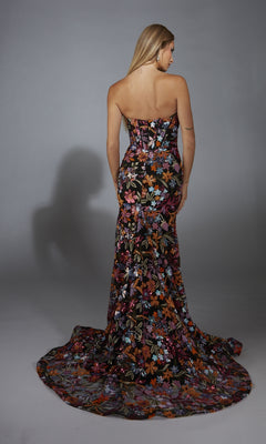 A woman faces away, wearing the Alyce 61810 long prom dress—a strapless mermaid gown with a sequin flower print and long train—against a neutral background.