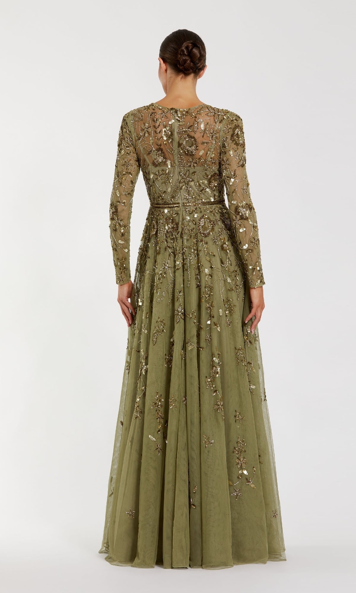 Woman wearing a long, olive green dress with intricate detailing on a white background