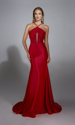 A woman stands against a plain light gray background wearing the Alyce 61820, a long prom dress featuring a fitted red silhouette with a corset bodice, halter neckline, and sheer panels for an elegant look.