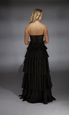 A woman faces away from a neutral background wearing the Long Prom Dress: Alyce 61833, featuring a strapless fitted sheer corset bodice and a ruffle tiered A-line skirt.