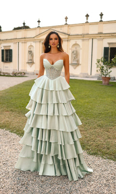 A woman stands outside a historic building wearing the Alyce 61833 long prom dress, featuring a strapless sheer corset bodice and a mint-green ruffle tiered A-line skirt.