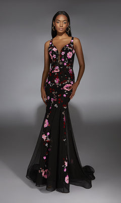 A woman models the Alyce 61839 long prom dress, a black floral mermaid gown with pink and red embroidery, against a plain gray background.