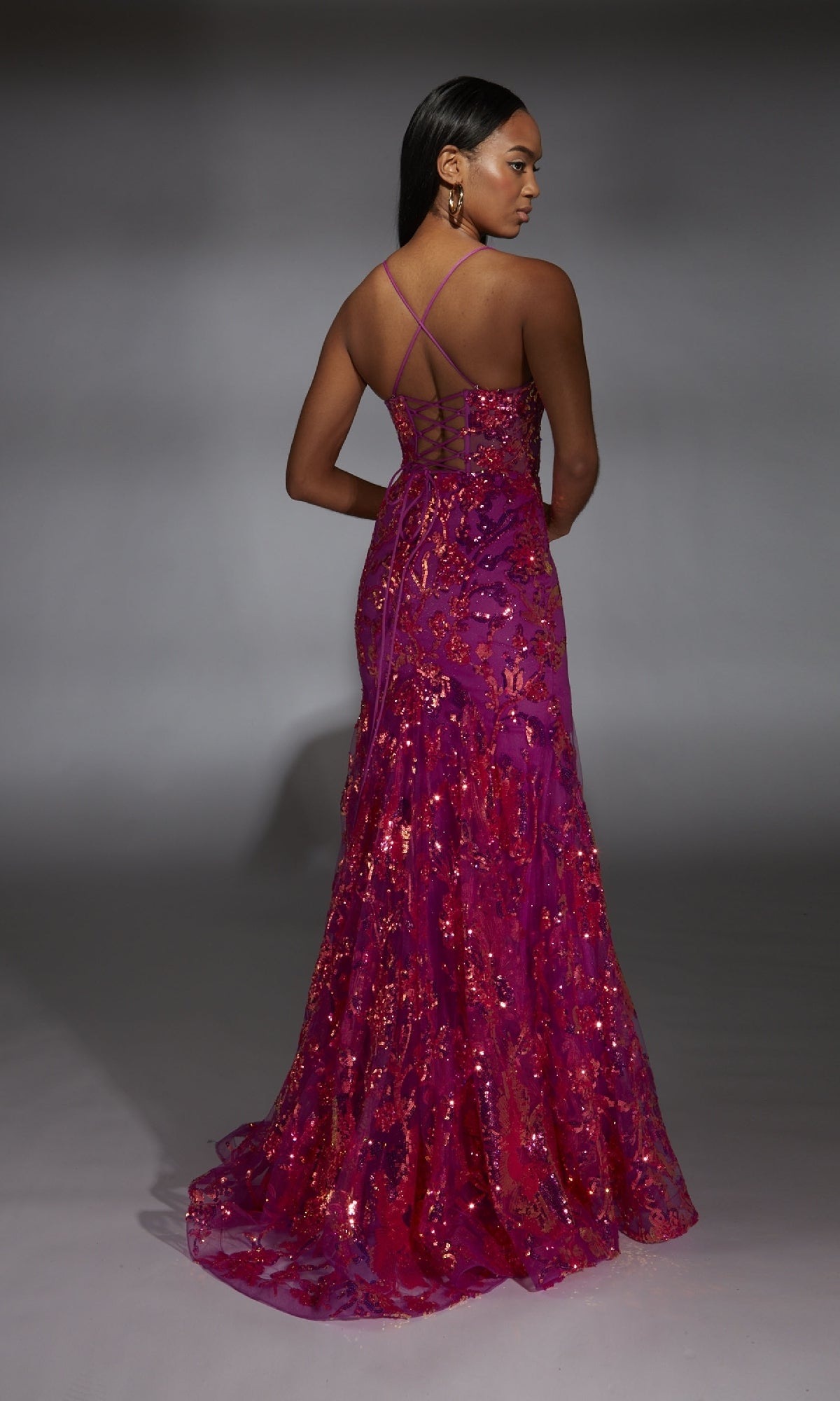 A woman faces away wearing the Alyce 61854 Long Prom Dress, a floor-length gown featuring a mermaid silhouette, sequin embellishments, and crisscross back straps.