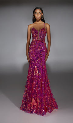 A woman wears the Alyce 61854 long prom dress, featuring neon pink sequins, thin straps, a fitted bodice, and a subtle mermaid silhouette, standing against a plain gray background.