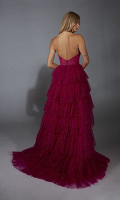 A woman stands with her back to the camera against a plain grey background, wearing the Alyce 61859 long prom dress—a strapless, backless magenta tiered gown with a corset bodice.