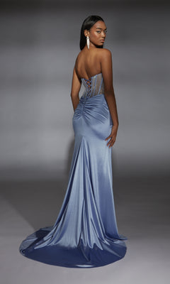 A woman faces away, wearing the Alyce 61863 Strapless Long Corset Prom Dress—a floor-length light blue satin gown with a fitted ruched back and sheer rhinestone-beaded corset bodice.