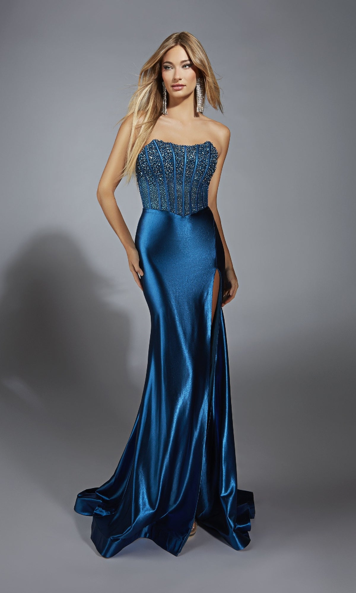 A woman in the Alyce 61879 strapless long satin prom dress featuring a beaded corset bodice and thigh-high slit stands against a plain gray background.