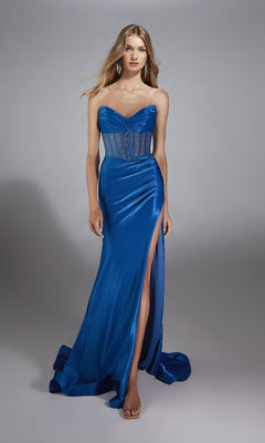 A woman stands against a gray background wearing the Alyce 61882, a long strapless blue prom dress with a sheer corset bodice, fitted floor-length skirt, and high thigh slit.