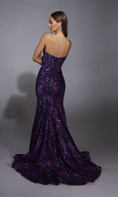 A woman poses with her back to the camera in the Alyce 61887 long prom dress, featuring a strapless mermaid silhouette, shimmering embellishments, and a slight train, set against a plain gray background.