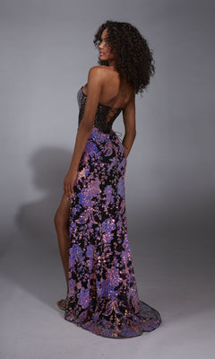 A woman poses in a studio wearing the Alyce 61898 Long Prom Dress, featuring a strapless purple and pink sequin floral print, beaded corset bodice, floor-length skirt with side slit, and looks over her shoulder.