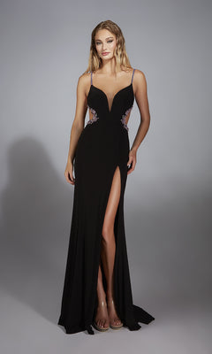 A woman stands against a plain gray background wearing the Alyce 61902, a sleeveless, floor-length black prom dress featuring a deep neckline, leg slit, butterfly back, and floral embellishments on the sides.