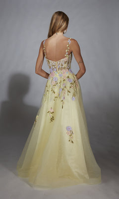 A woman faces away in the Alyce 61909, a light yellow long prom dress with a floral lace corset, embroidered sheer back, and an A-line tulle skirt, set against a plain gray background.