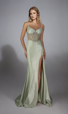A woman models the Alyce 61916 long prom dress featuring a light green shimmer fabric, beaded corset bodice, spaghetti straps, and high thigh slit, standing against a plain gray background.