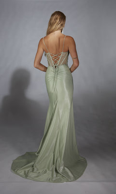A woman stands facing away against a plain background, wearing the Alyce 61916—a light green, floor-length shimmer prom dress featuring a lace-up back.