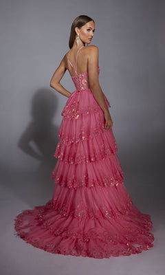 Model poses with her back turned, looking over her shoulder, in the Alyce 61927 Long Prom Dress—a floor-length pink gown featuring tiers, floral embellishments, and a sheer corset bodice—set against a plain gray background.