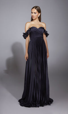 A woman models the Alyce 61946 long prom dress—an off-the-shoulder, floor-length A-line gown with pleats, ruffled sleeves, and a sweetheart neckline—against a plain gray background.