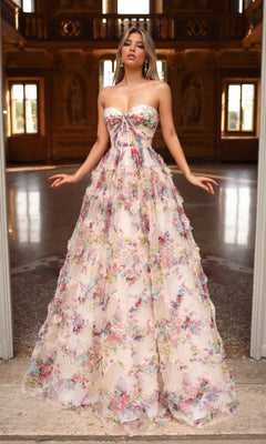 A woman stands in an ornate hall wearing the Alyce 61957 long prom dress, which features a strapless floral design with a delicate corset bodice and a flowing A-line skirt in soft pastel hues.