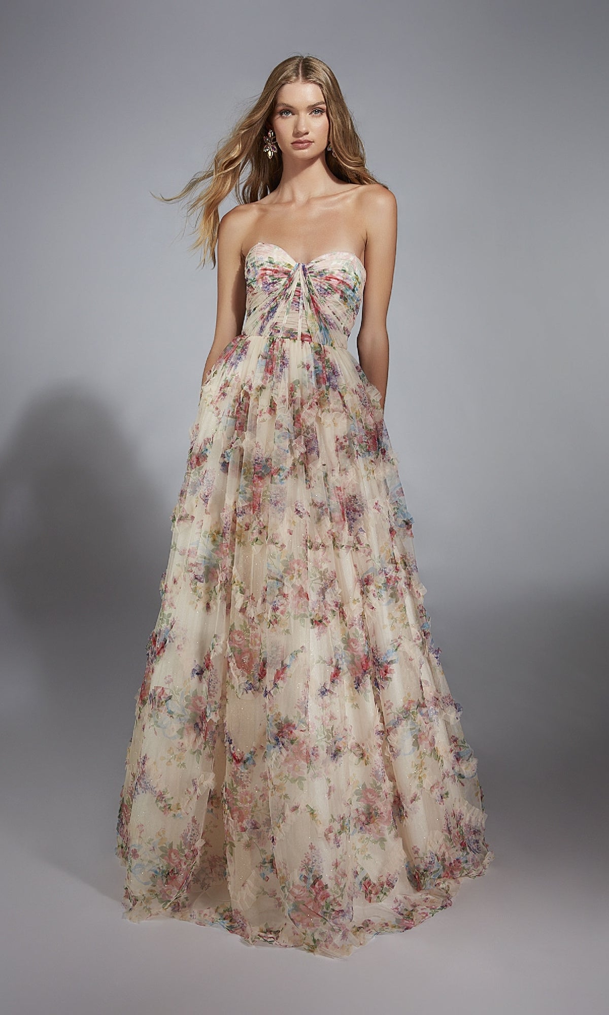 A woman poses against a plain gray background in the Alyce 61957, a long prom dress featuring a strapless floral bodice and elegant A-line skirt.