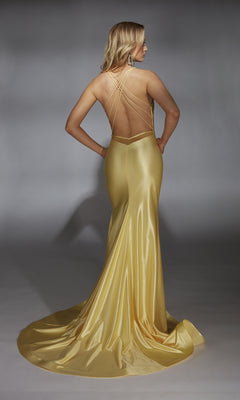 A woman with flowing blonde hair faces away in the Alyce 61966 Long Prom Dress, a shiny gold satin gown featuring a low back, V-neckline, thin crisscross straps, a slight train, and floor-length design.