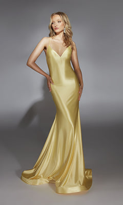 Woman wearing the Alyce 61966 long prom dress—sleeveless, floor-length gold satin with a fitted bodice, v-neckline, and flowing skirt—stands against a plain gray background.