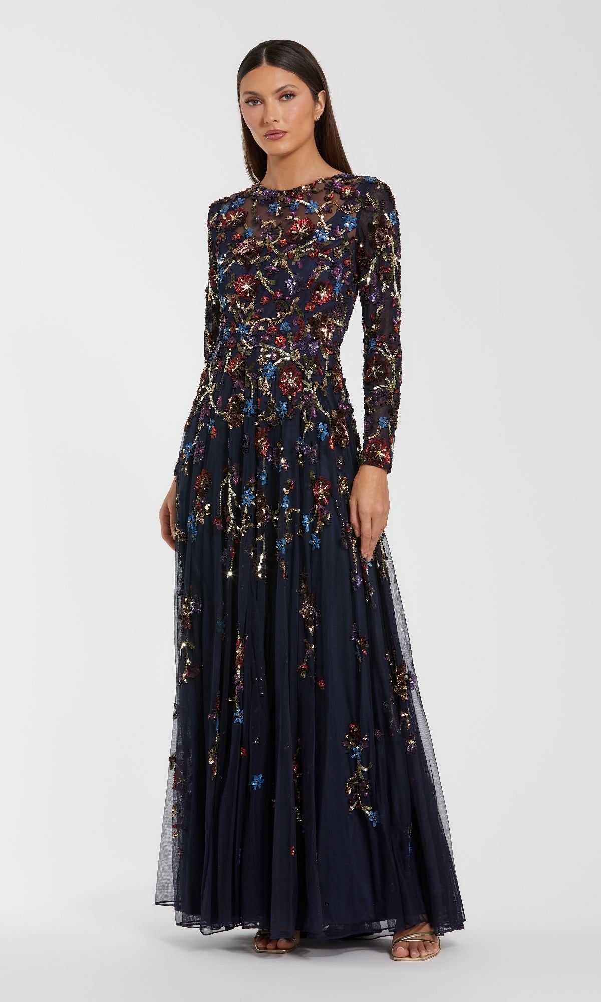 Woman wearing a long, dark blue evening gown with floral patterns on a white background
