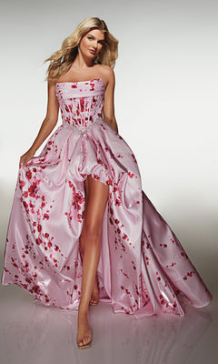 A woman wears the Alyce 61989 long prom dress—strapless, pale pink satin with red floral patterns, a corset bodice, and high-leg slit—while standing against a neutral background.