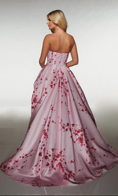 A woman wearing the Alyce 61989 long prom dress stands facing away, highlighting the strapless satin floral gown’s corset bodice and flowing skirt.