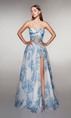 Woman in the Alyce 61994 long prom dress, featuring blue and white floral print, a sheer corset bodice, crisscross straps, and high slit, stands with hands on hips against a plain background.