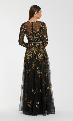 Woman showing the back of a black floral evening gown she's wearing in front of a white background