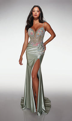 A woman stands against a plain background wearing the Alyce 62022 long prom dress—a light green, sleeveless gown with a corset bodice, high-leg slit, and floral embellishments.