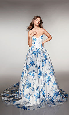 A woman models the Alyce 62026 long prom dress, a strapless, floor-length white ballgown with elegant blue floral patterns, set against a plain background.