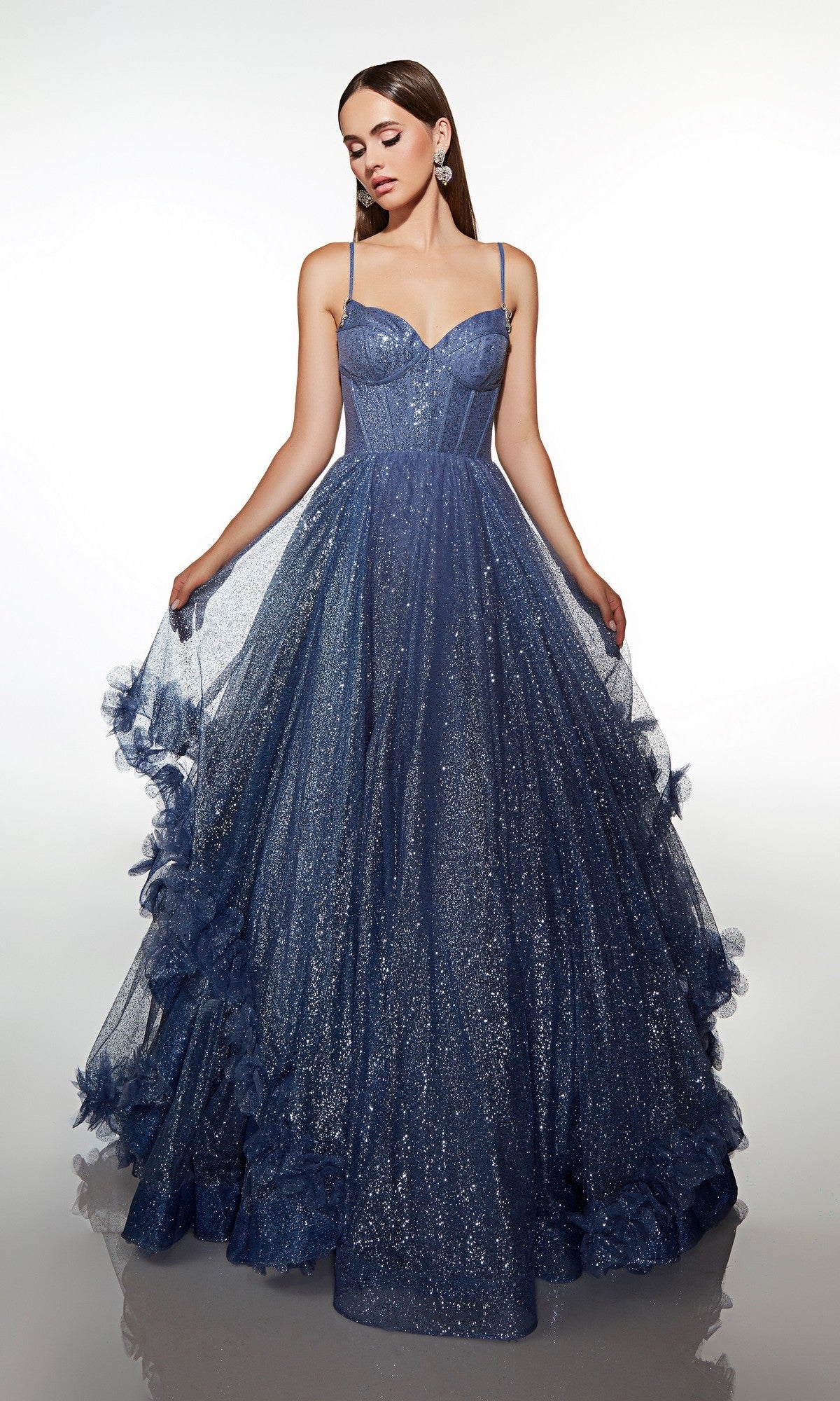 A woman poses in the Alyce 62032 Long Prom Dress in Storm Cloud, featuring a fitted bodice, thin straps, and a floor-length glitter tulle skirt with ruffles against a plain background.