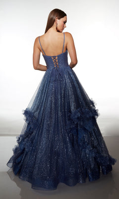A woman faces away, wearing the Alyce 62032—a navy blue glitter tulle ball gown with thin straps, a lace-up corset bodice, and ruffled tulle detailing on the skirt.